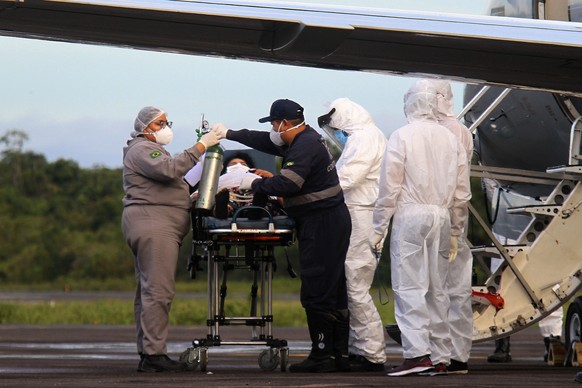 Healthcare workers and military prepare to board a COVID-19 patient onto an air force plane, at the Ponta Pelada Airport, in Manaus, Amazonas state, Brazil, Friday, Jan. 15, 2021. Some hope for Manaus ...