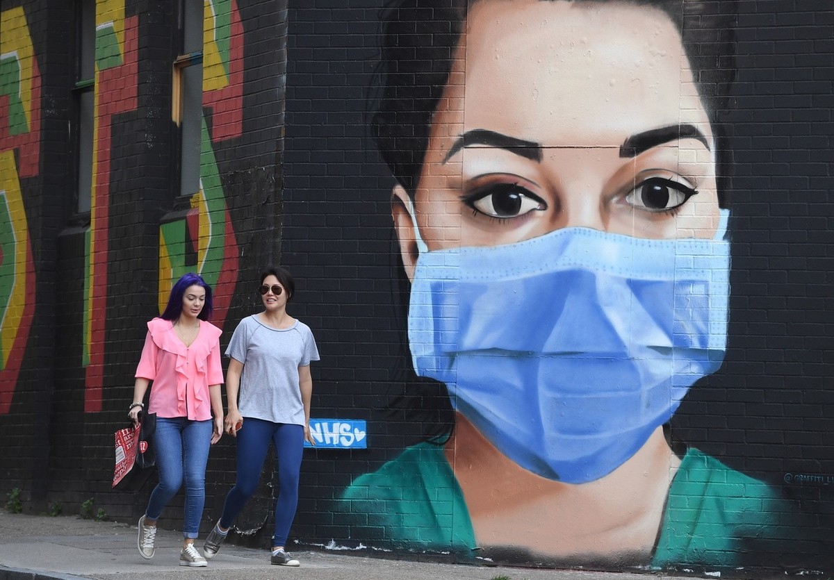 epa08377979 Pedistrians walk past an artwork depicting a nurse in wearing a face mask in east London, Britain, 22 April 2020. British Prime Minister Johnson has announced that Britons can only leave t ...