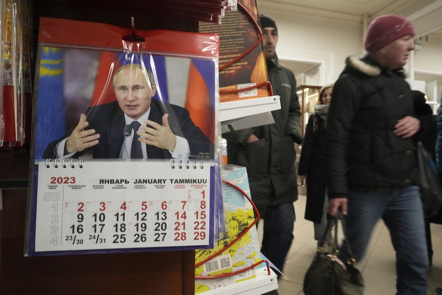 People walk past a calendar for 2023 depicting Russian President Vladimir Putin displayed for sale in a shop in St. Petersburg, Russia, Wednesday, Nov. 16, 2022. (AP Photo/Dmitri Lovetsky)