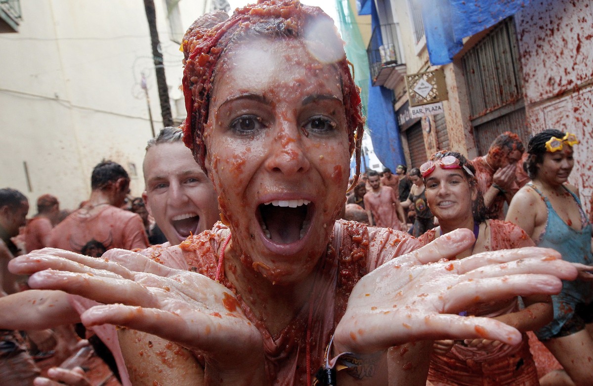 epa06171502 A woman covered in squashed tomatoes takes part in the traditional tomato fight called 'Tomatina' in Bunol, Spain, 30 August 2017. As every year on the last Wednesday of August,  ...