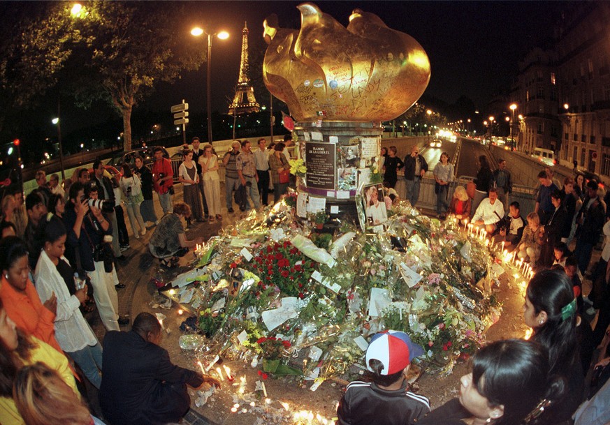 People gather for a vigil around the makeshift monument for Diana, Princess of Wales, in Paris Monday, Aug. 31, 1998. Diana died last August 31 when the car crashed at high speed inside the Pont de l& ...