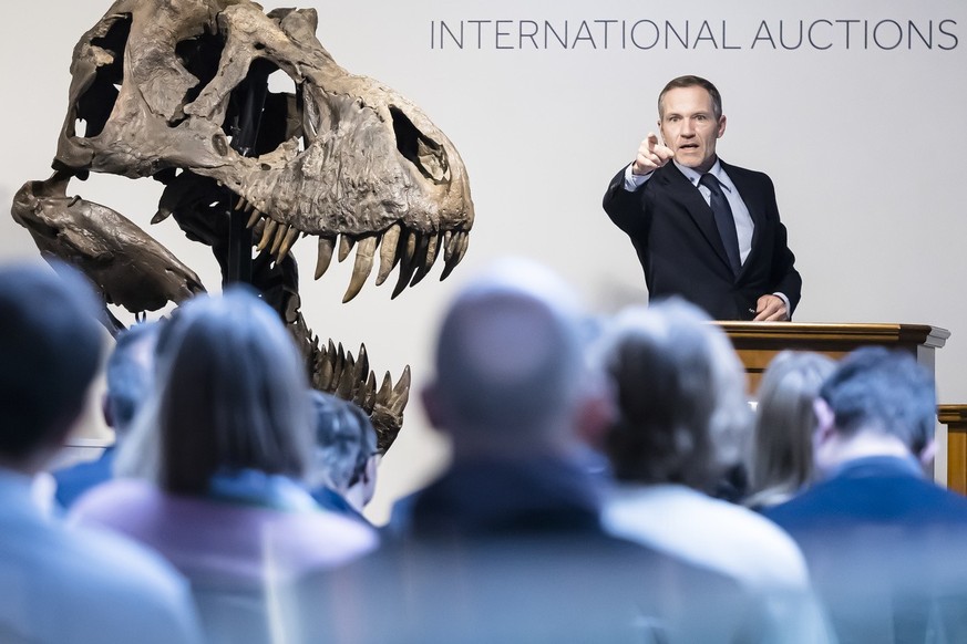 Cyril Koller, CEO auction house Koller, gestures next to the head of the skeleton of a Tyrannosaurus rex named Trinity, during an auction of the auction house Koller in Zurich, Switzerland on Tuesday, ...