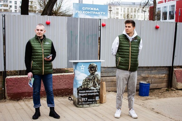 MOSCOW, RUSSIA - 2023/04/13: Two volunteers operate a mobile army recruitment spot set up on a crowded path near a train stop in Moscow, Russia. 
They distribute leaflets and brochures to interested p ...