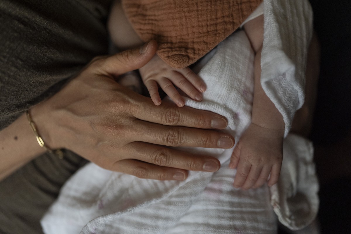 Robyn Joy Park, an adoptee from South Korea, gently pats her newborn daughter, Rae, at her home in Pasadena, Calif., Friday, April 19, 2024. (AP Photo/Jae C. Hong)