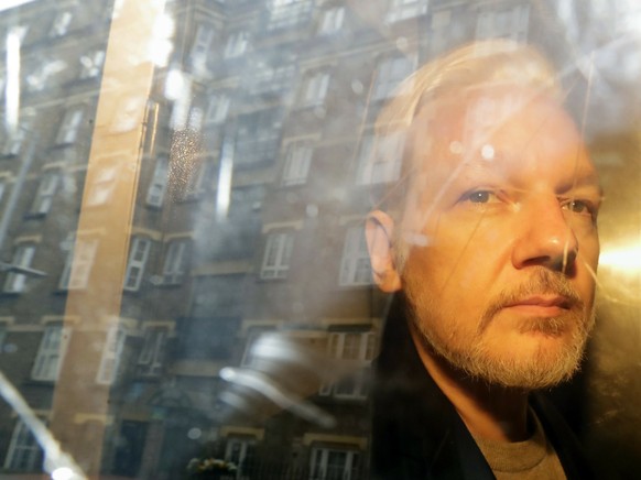 FILE - In this May 1, 2019 file photo buildings are reflected in the window as WikiLeaks founder Julian Assange is taken from court, where he appeared on charges of jumping British bail seven years ag ...