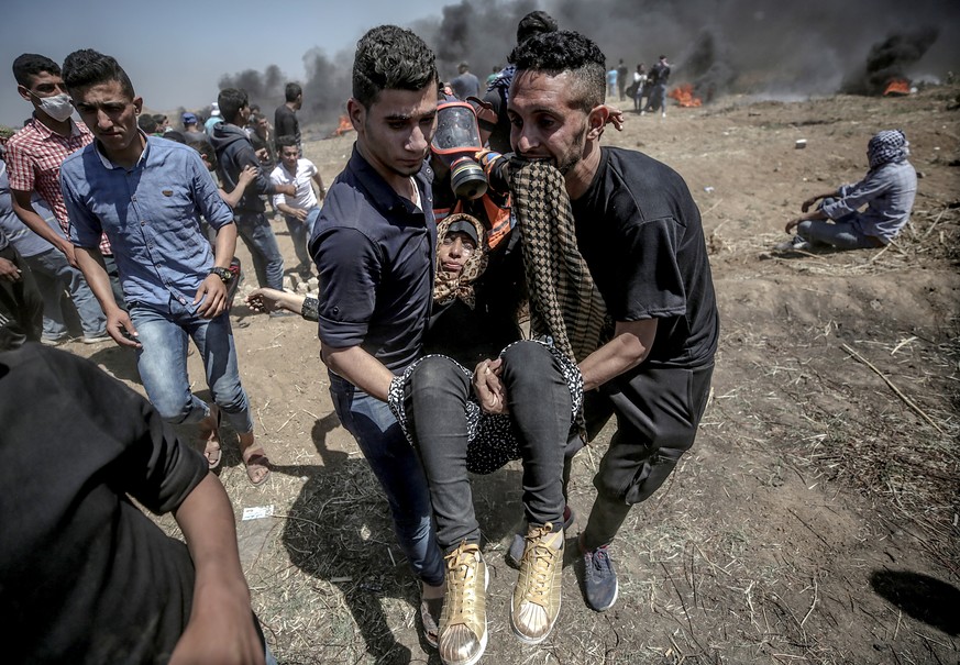 epa06737538 Palestinian protesters carry a wounded female protester during clashes after protests near the border with Israel in the east of Gaza Strip, 14 May 2018 (issued 15 May 2018). More protests ...
