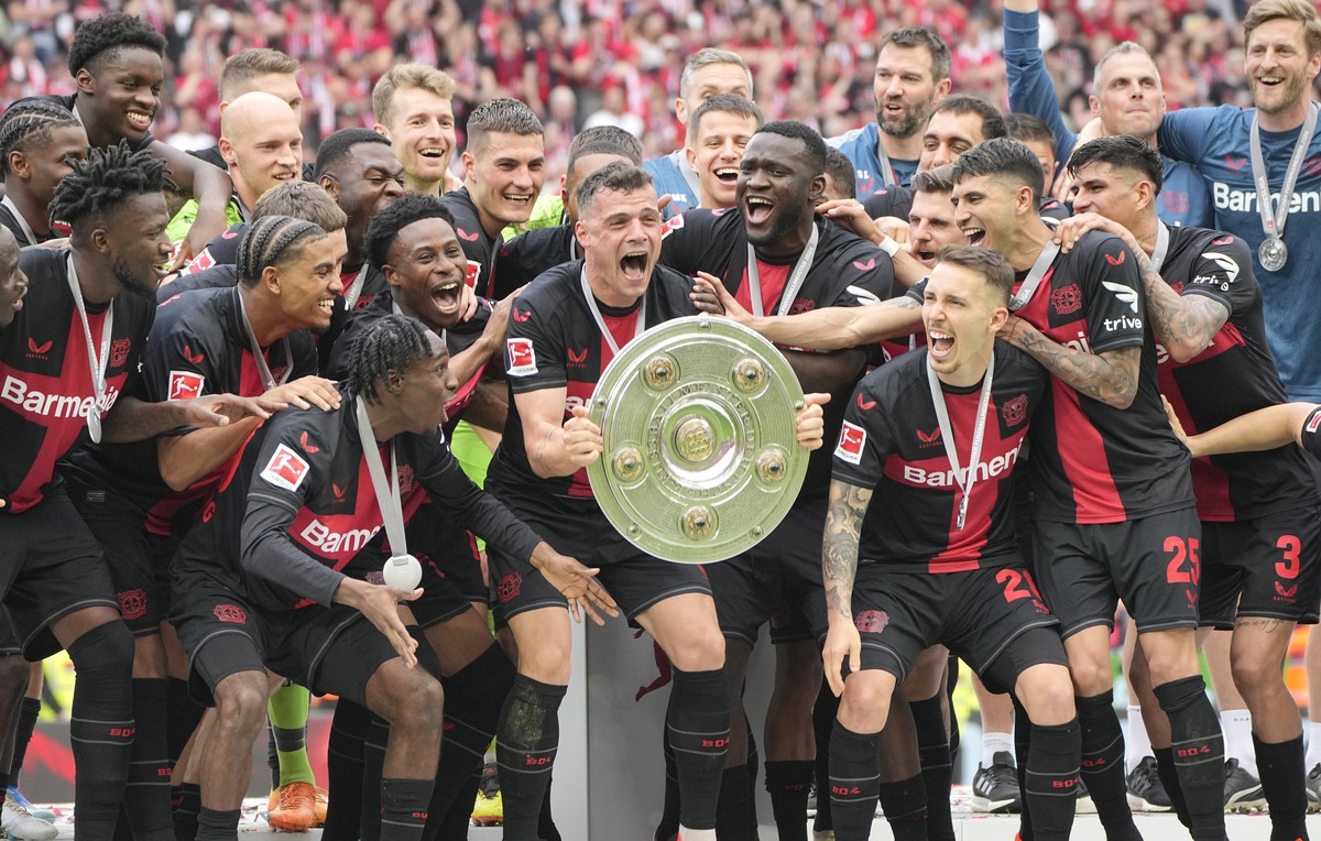 Leverkusen's Granit Xhaka, centre, celebrates with the trophy as his team won the German Bundesliga soccer match between Bayer Leverkusen and FC Augsburg at the BayArena in Leverkusen, Germany, S ...