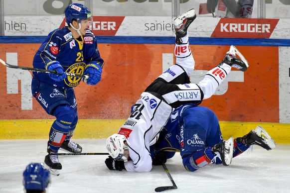 Luganos Dominic Lammer, oben, fliegt ueber den Davoser Benjamin Baumgartner, beobachtet vom Davoser Dominic Buchli, beim Eishockey-Qualifikationsspiel der National League A zwischen dem HC Davos und d ...