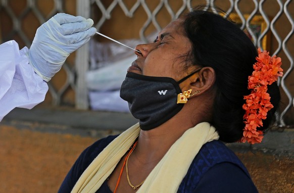 epa09161638 A health worker takes a nasal swab sample of a woman for COVID-19 test in Bangalore, India, 26 April 2021. The Karnataka government is contemplating a partial lockdown of the city in the w ...