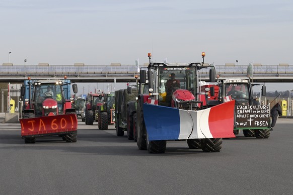 Farmers drive their tractors a highway leading to Paris, Monday, Jan. 29, 2024 near Chamant, north of Paris. Protesting farmers vowed to encircle Paris with tractor barricades and drive-slows on Monda ...