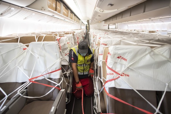 Workers unload boxes containing facial masks and medical syringe pump from China from an aircraft Boeing 777 of Swiss International Air Lines at the Zurich Aeroport, in Zurich, Switzerland, Monday, April 27, 2020.  (KEYSTONE/Ennio Leanza)