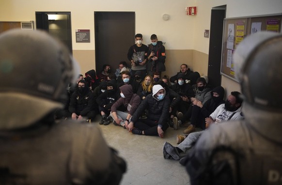 Rap singer Pablo Hasél, background, is surrounded by his supporters as police officers try to arrest him at the University of Lleida, Spain, Tuesday, Feb. 16, 2021. A rapper in Spain and dozens of his ...