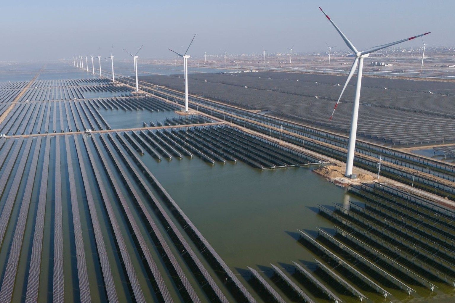 FILE - Wind turbines operate along a solar farm near Weifang in eastern China's Shandong province on March 22, 2024. (AP Photo/Ng Han Guan, File)
