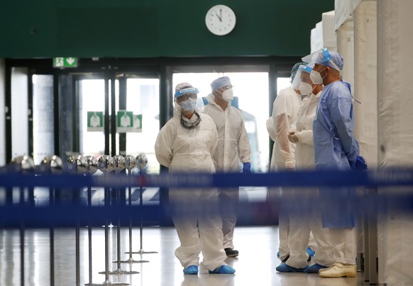 FILE - In this Aug. 20, 2020 file photo medical workers wearing protective gear wait to collect swabs from a passenger arriving from one of four Mediterranean countries, Croatia, Greece, Malta and Spa ...