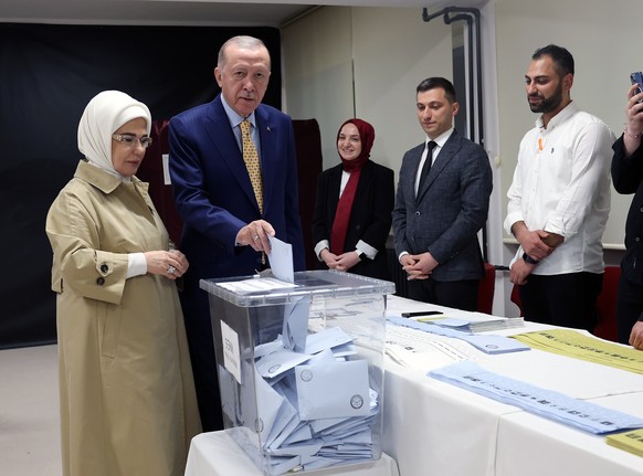 epa11252627 A handout photo made available by the Turkish President's Press Office shows Turkish President Recep Tayyip Erdogan (C) and his wife Emine Erdogan (L) voting at a polling station during the…