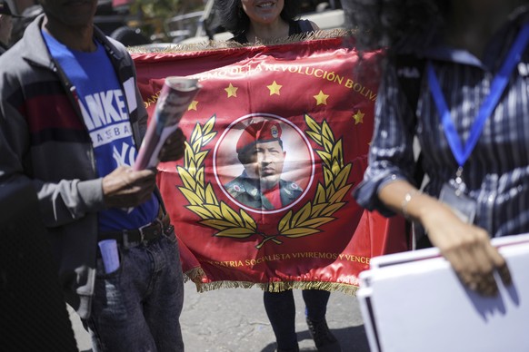 People hold a flag with the image of late Venezuelan President Hugo Chavez during commemorations marking the tenth anniversary of his death, at the Cuartel de la Monta�a 4F where his remains are inter ...