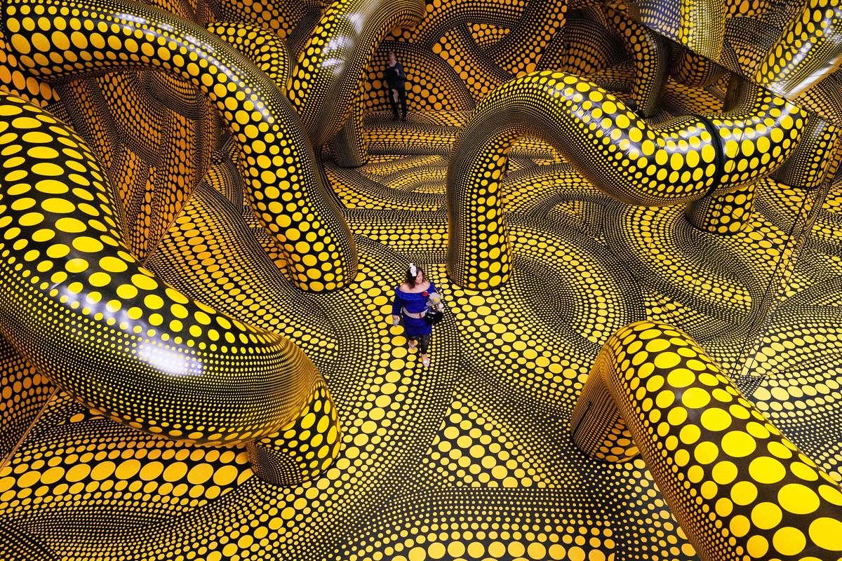 People walk through the artwork 'Infinity Mirrored Room' during a preview of the new major exhibition of legendary Japanese artist Yayoi Kusama at the Museum Ludwig in Cologne, Thursday, Mar ...