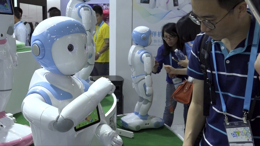 In this image taken from video, visitors look at iPal robots during the Shanghai CES electronic show in Shanghai, China, Thursday, June 8, 2017. More than 50 companies are showcasing a new generation  ...