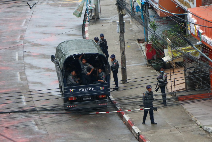 Police security forces stand by inside a police vehicle and on the sidewalk of Hledan Road in Kamayut township in Yangon, Myanmar Friday, April 16, 2021. Opponents of Myanmar