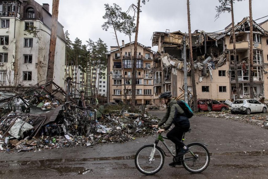 IRPIN, UKRAINE - MARCH 03: A man rides his bike past destroyed buildings on March 03, 2022 in Irpin, Ukraine. Russia continues assault on Ukraine&#039;s major cities, including the capital Kyiv, a wee ...