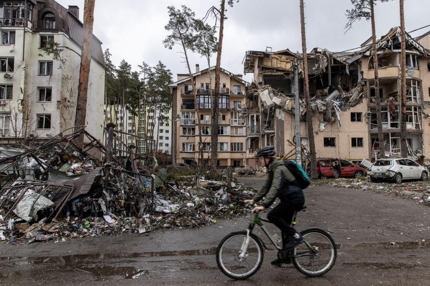 IRPIN, UKRAINE - MARCH 03: A man rides his bike past destroyed buildings on March 03, 2022 in Irpin, Ukraine. Russia continues assault on Ukraine's major cities, including the capital Kyiv, a wee ...
