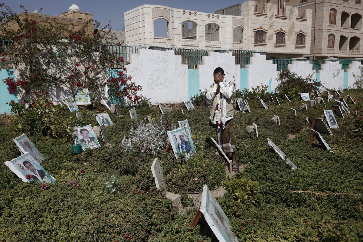 epa09048800 Recently released-Houthi prisoner Abdullah Al-Muntasir prays at the graves of his slain comrades who were killed in ongoing fighting, at a cemetery in Sana'a, Yemen, 03 March 2021. Ab ...