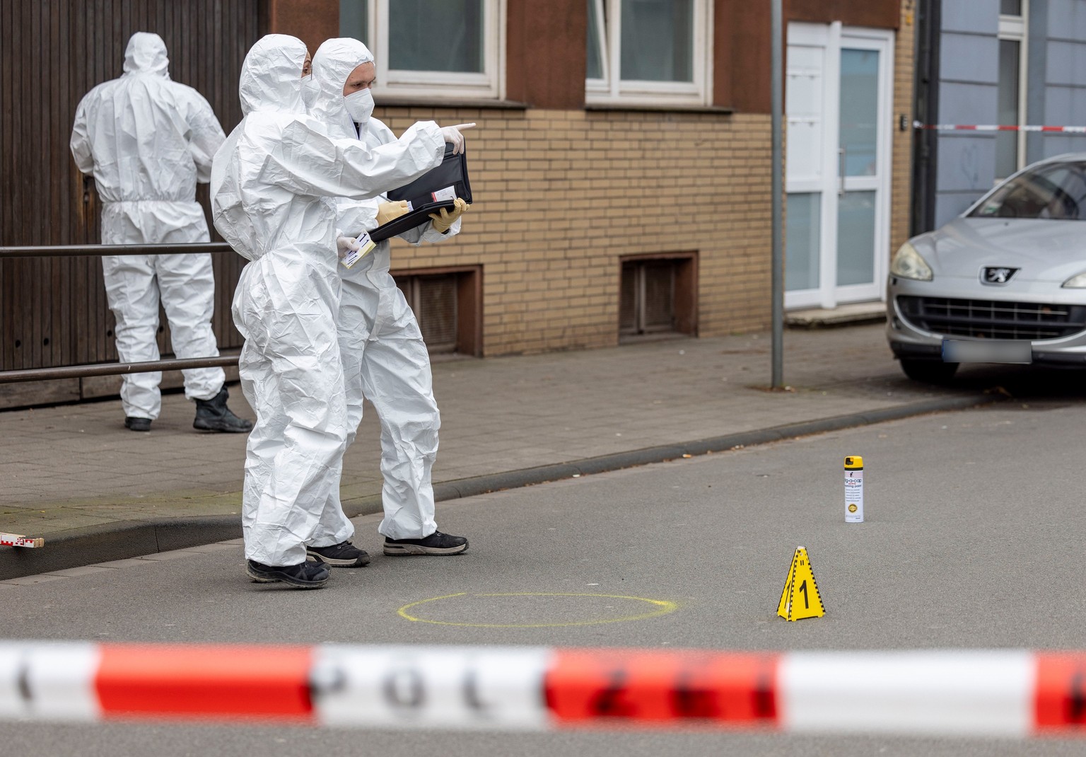 dpatopbilder - 28.02.2024, Nordrhein-Westfalen, Duisburg: Beamte der Spurensicherung stehen am Tatort des Angriffs auf zwei Kinder, einige Meter von einer Schule entfernt. Auf einem kleinen Parkplatz  ...