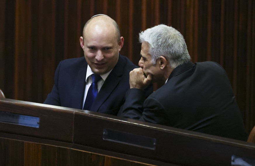 Yamina party leader Naftali Bennett, left, smiles as he speaks to Yesh Atid party leader Yair Lapid during a special session of the Knesset, whereby Israeli lawmakers elect a new president, at the ple ...