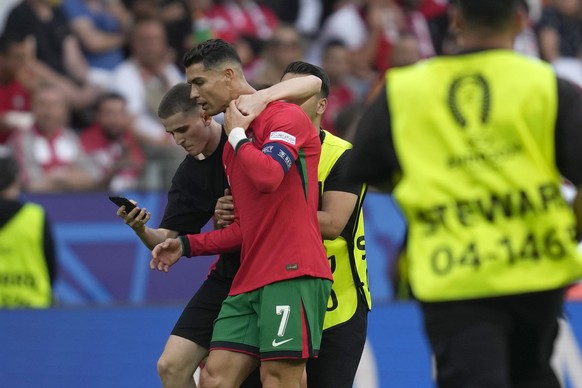 A pitch invader tries to take a selfie with Portugal&#039;s Cristiano Ronaldo as a steward moves him out during a Group F match between Turkey and Portugal at the Euro 2024 soccer tournament in Dortmu ...
