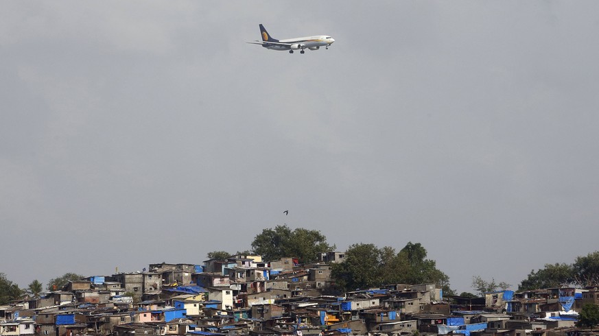 FILE- In this June 15, 2016 file photo, an aircraft of Indias private airline Jet Airways flies above shanties adjacent to the Chhatrapati Shivaji airport as it prepares to land in Mumbai, India. Ind ...