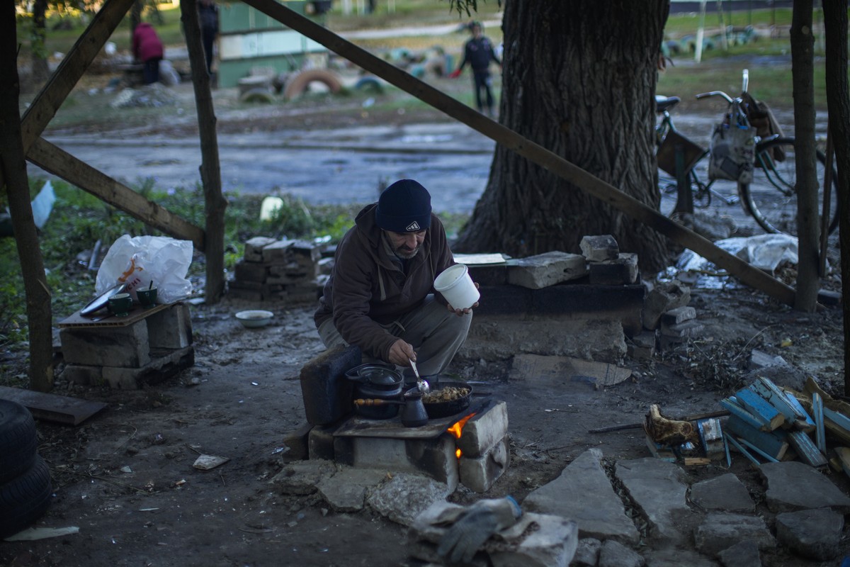 A man cooks on a makeshift stove in Kivsharivka, Ukraine, Sunday, Oct. 16, 2022. Residents in Kivsharivka have been living with no gas, electricity or running water supply for around three weeks. (AP  ...