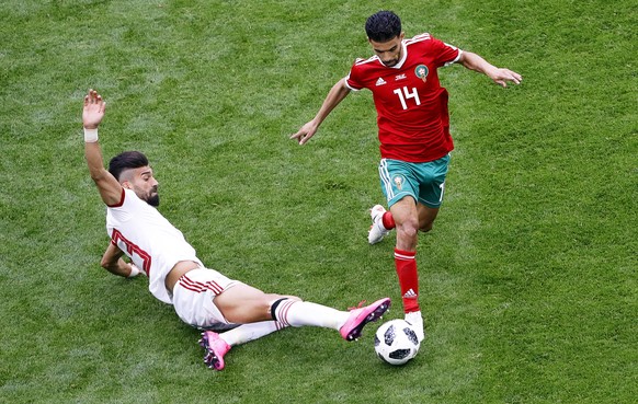 epa06810703 Ramin Rezaeian (L) of Iran in action against Mbark Boussoufa (R) of Morocco during the FIFA World Cup 2018 group B preliminary round soccer match between Morocco and Iran in St.Petersburg, ...
