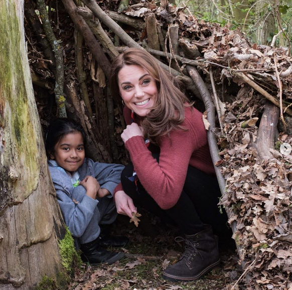 Kate erschrickt ein bisschen über das Kind, das plötzlich aus dem Baum kriecht. Doch sie lässt sich nichts anmerken und versucht, den Schreck mit einem natürlichen Lächeln zu überspielen.