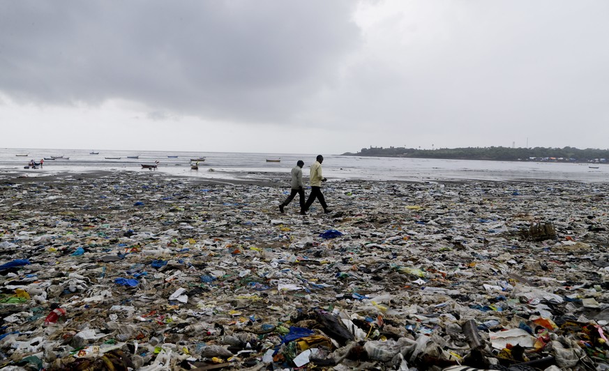 In this Aug. 19, 2017 photo, people walk past garbage at the Versova beach on the Arabian Sea coast in Mumbai, India. The 2.5-kilometer (approximately 1.5 miles) stretch of Mumbai’s Versova beach was  ...