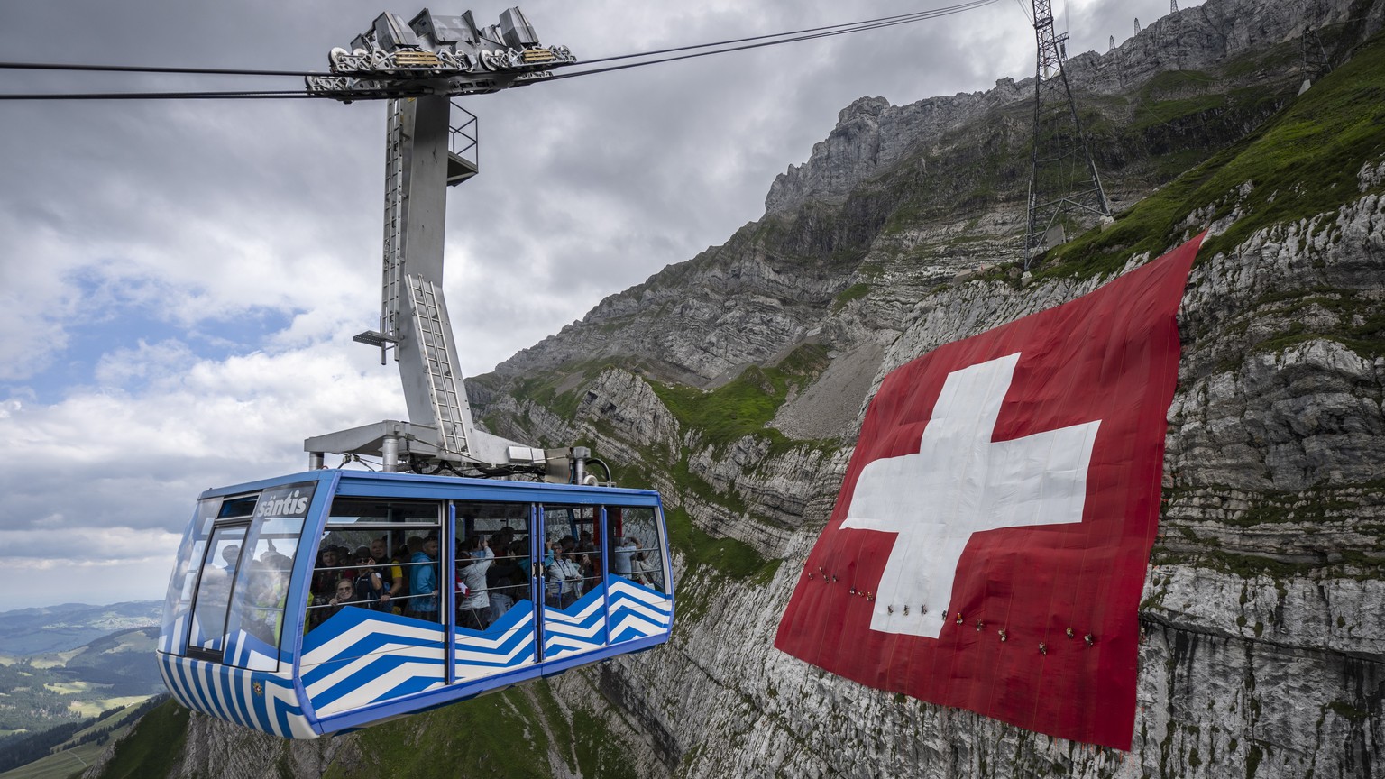 epa10099774 An 80x80 meter Swiss flag hangs on a rock face below the Saentis mountain, one day before the country&#039;s national holiday, on the Schwaegalp, Switzerland, 31 July 2022. Switzerland cel ...