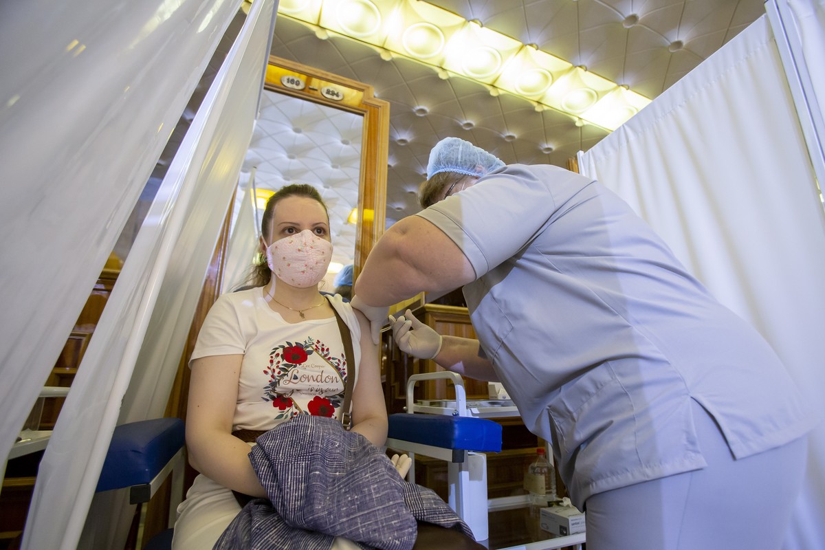 epa09302692 A health worker administers a dose of Russia's Sputnik V (Gam-COVID-Vac) vaccine against COVID-19 to a woman at the vaccination point in the warderobe zone at the Republican Palace in ...