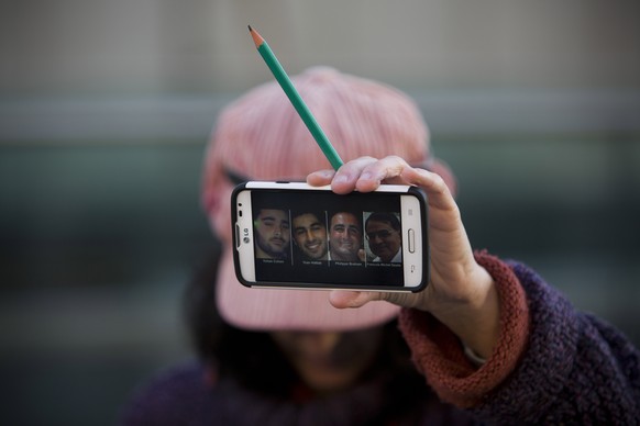 Eine Frau zeigt die Fotos der vier Opfer vom koscheren Supermarkt.&nbsp;Lassana Bathily verhinderte, dass es noch mehr Tote gab.&nbsp;