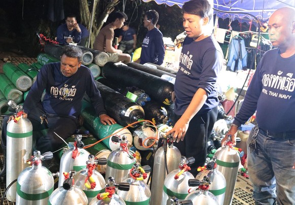 epa06870523 A handout photo made available by the Thai Royal Navy on 07 July 2018 shows Thai Navy personnel preparing oxygen tanks for the ongoing rescue operations for the youth soccer team and their ...