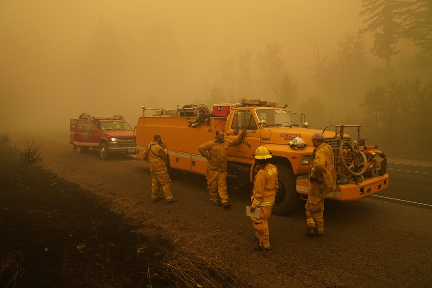 Firefighters with the Monitor Fire Department wait alongside the road surrounded by smoke in an area destroyed by a wildfire Saturday, Sept. 12, 2020, near Mill City, Ore. (AP Photo/John Locher)