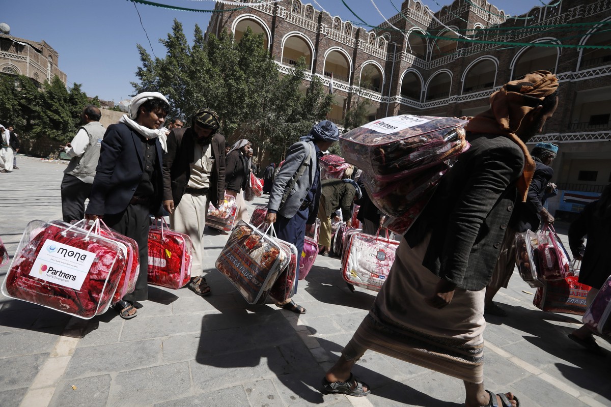 epa09564033 War-affected Yemenis receive blankets distributed by a local relief agency in preparation for winter in Sana'a, Yemen, 04 November 2021. The Mona relief agency began distributing blan ...