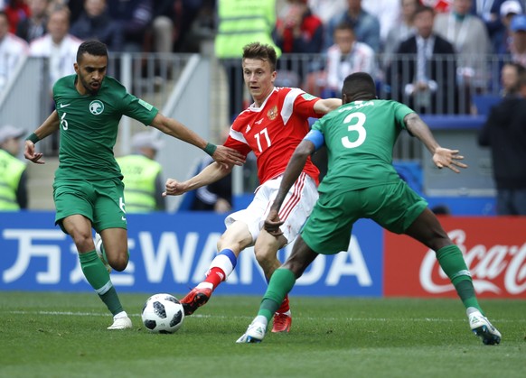 Russia&#039;s Roman Zobnin, centre, challenges for the ball with Saudi Arabia&#039;s Mohammed Alburayk, left, and Saudi Arabia&#039;s Osama Hawsawi during the group A match between Russia and Saudi Ar ...