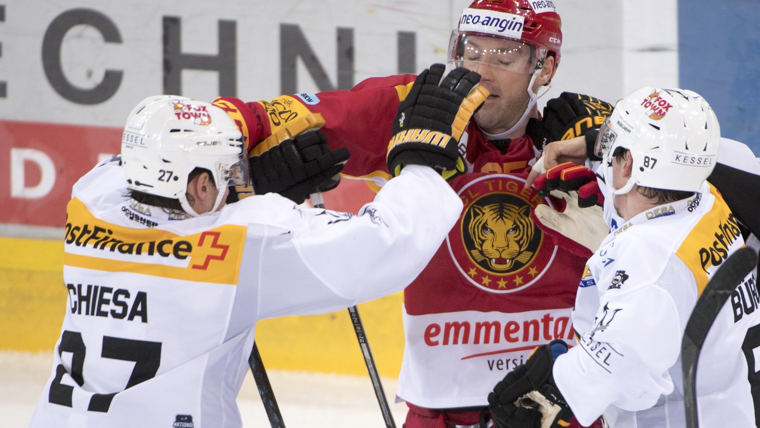 Langnaus Cam Barker, Mitte, kaempft gegen Luganos Alessandro Chiesa, links, und Dario Buergler, rechts, waehrend dem Meisterschaftsspiel der National League zwischen den SCL Tigers und dem HC Lugano,  ...