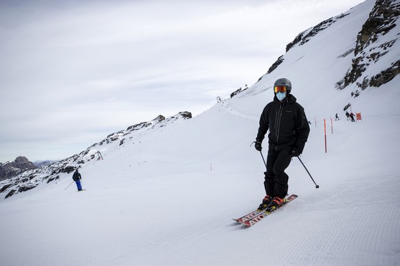 Ein Skifahrer mit Atemschutzmaske faehrt Ski auf dem Titlis, am Dienstag, 10. November 2020. Auf allen Sesselbahnen, Skiliften und Seilbahnen des Skigebietes gilt Maskenpflicht. (KEYSTONE/Alexandra We ...