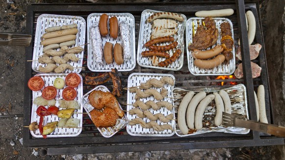 Friends are meeting for a cosy barbecue in a community center in Zurich, Switzerland, on May 25, 2011. They gather around an open fire pit in the garden.The sausages and the barbecue meat laying on th ...