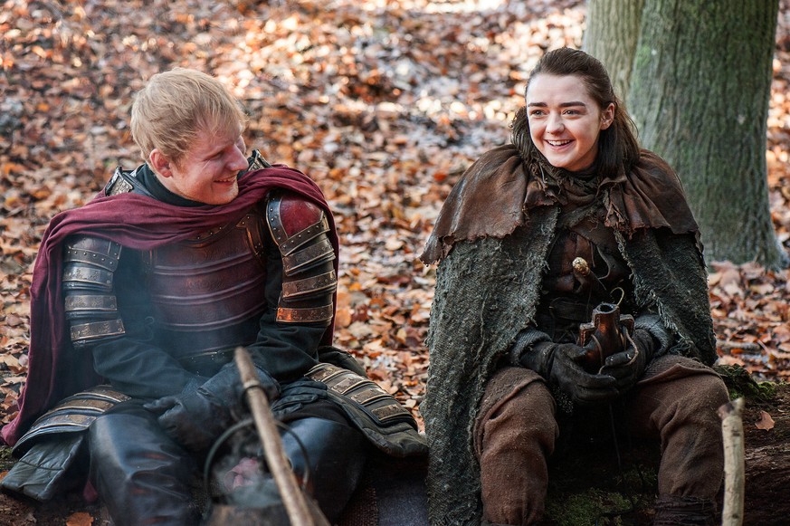 This image released by HBO shows Ed Sheeran, left, and Maisie Williams in a scene from &quot;Game of Thrones.&quot; Sheeran appeared as a Lannister soldier leading a group in song in the season premie ...