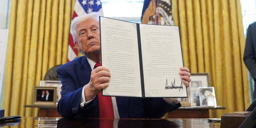 President Donald Trump holds a signed executive order in the Oval Office of the White House Wednesday, April 9, 2025, in Washington. (Pool via AP)
Trump
