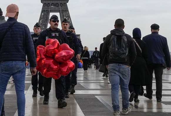 A police officer walks around Trocadero Square near the Eiffel Tower in Paris on Tuesday with confiscated balloons.  August 17, 2023. France raises its terror alert level in the wake of the school attack in…