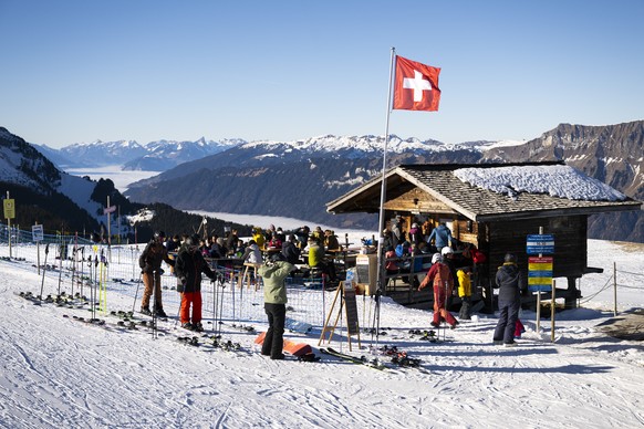 Menschen geniessen die Sonne ueber dem Nebelmeer, auf der Terrasse der Snackbar Windegg Spycher, am Montag, 29. Dezember 2025, auf den Skipisten von Axalp. (KEYSTONE/Anthony Anex)