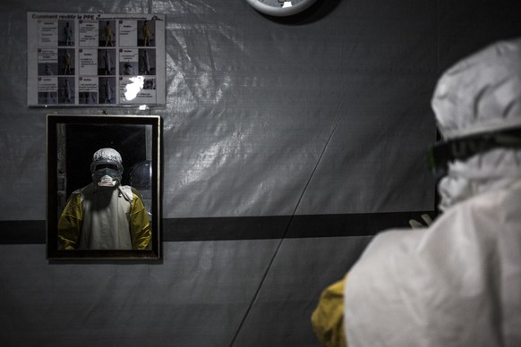 In this photo taken Saturday, Nov. 3, 2018 and made available Tuesday, Dec. 4, 2018, a health worker is seen wearing his personal protective equipment before entering the red zone of a Medecins Sans F ...