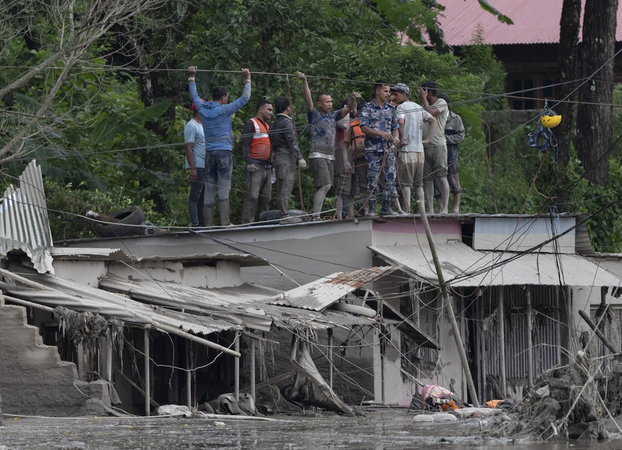 epa13193011 Rescuers gather on a rooftop as floodwaters sweep through Trishuli Bazar following a flash flood, in Nuwakot district, Nepal, 26 August 2026. Several people were killed and multiple others ...